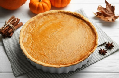 Photo of Delicious pumpkin pie and ingredients on white wooden table