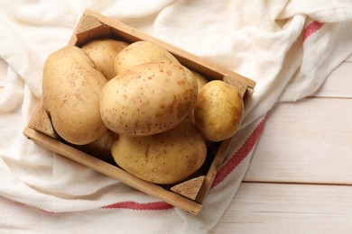 Photo of Raw fresh potatoes with crate on light wooden table, top view