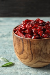 Wooden bowl with cranberries on table, closeup. Dried fruit as healthy snack