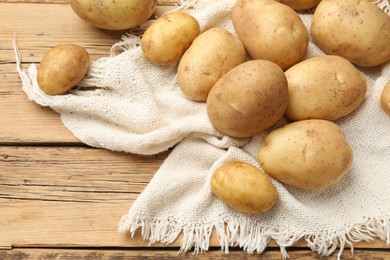 Photo of Raw fresh potatoes and napkin on wooden table