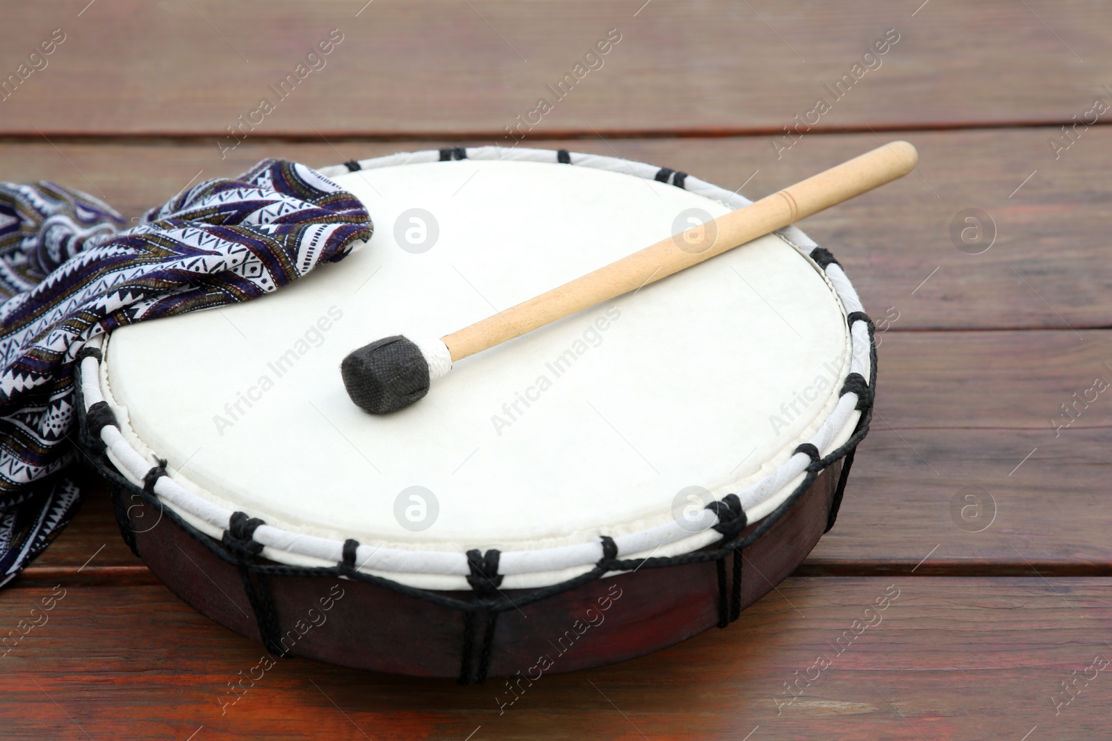 Photo of Modern drum with drumstick on wooden table