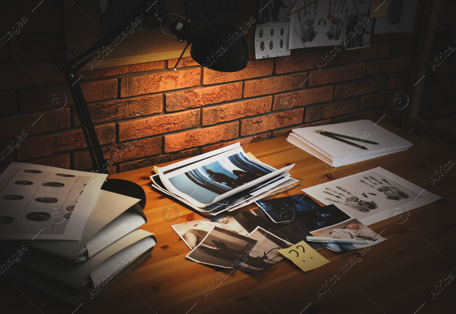 Photo of Detective workplace with documents, fingerprints and crime scene photos in office