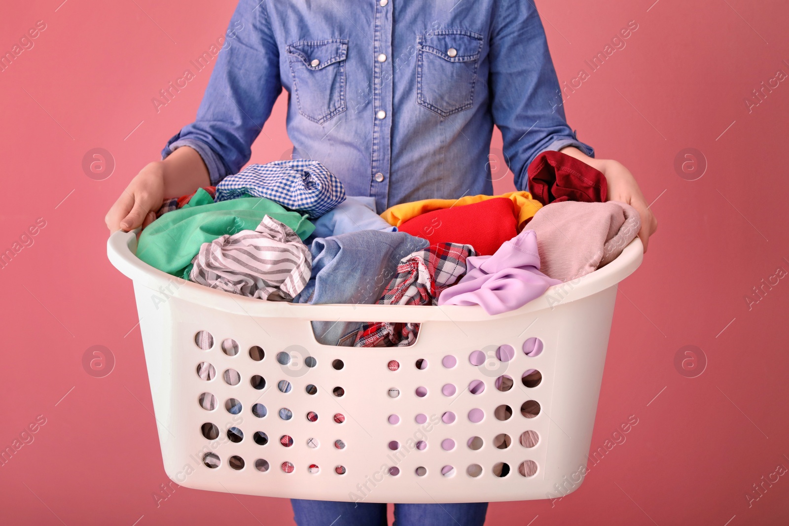 Photo of Woman holding laundry basket with dirty clothes on color background