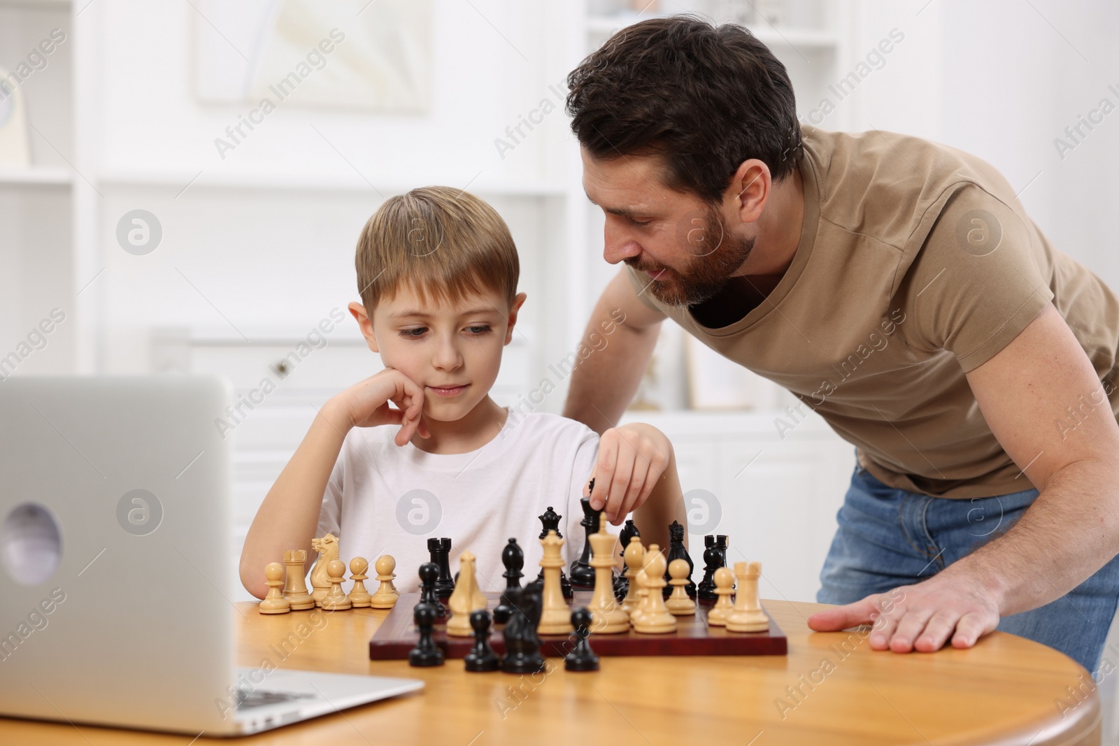 Photo of Father teaching his son to play chess following online lesson at home