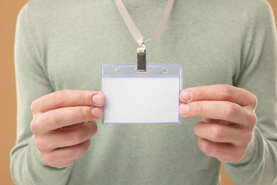 Man with blank badge on light brown background, closeup