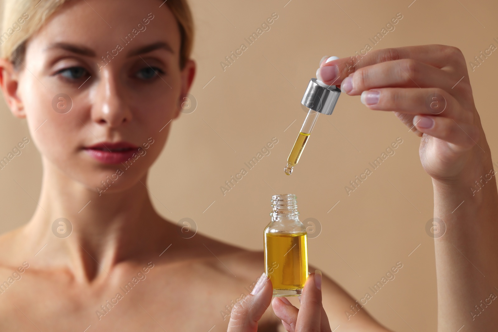 Photo of Beautiful woman with cosmetic serum in her hands on beige background