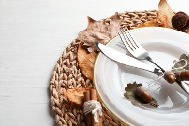 Autumn table setting with dry leaves on wicker mat, closeup