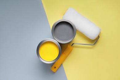 Photo of Cans with different paints and roller on color background, flat lay