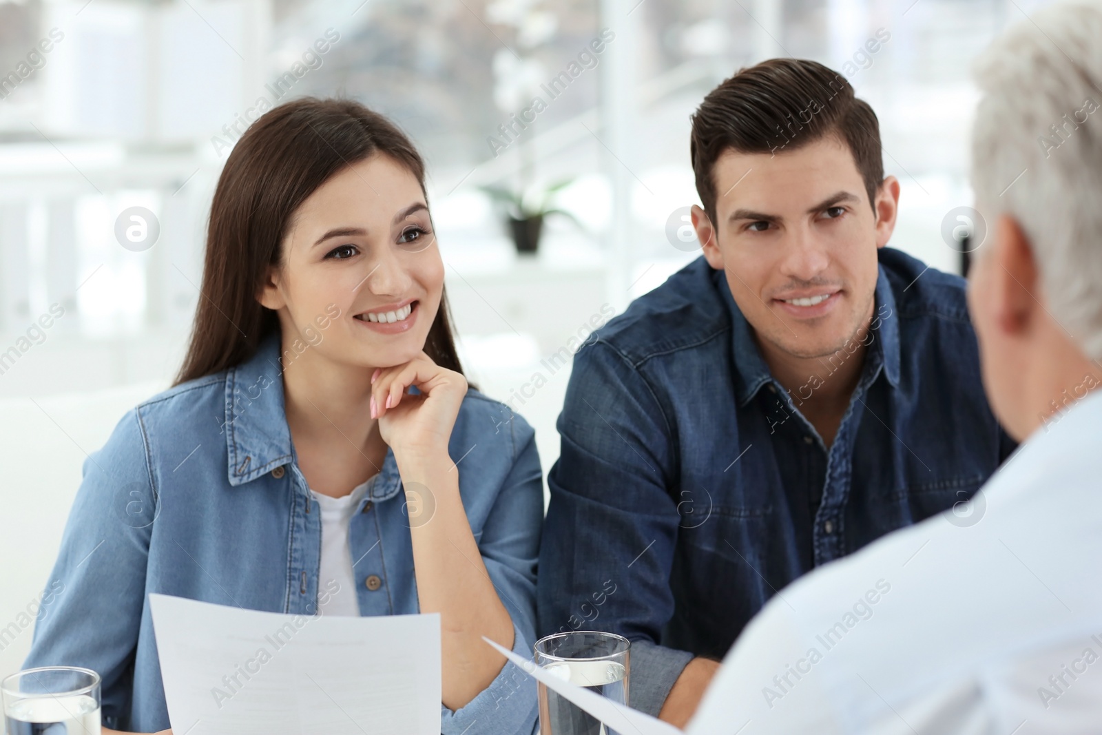 Photo of Young couple discussing pension plan with mature consultant in office