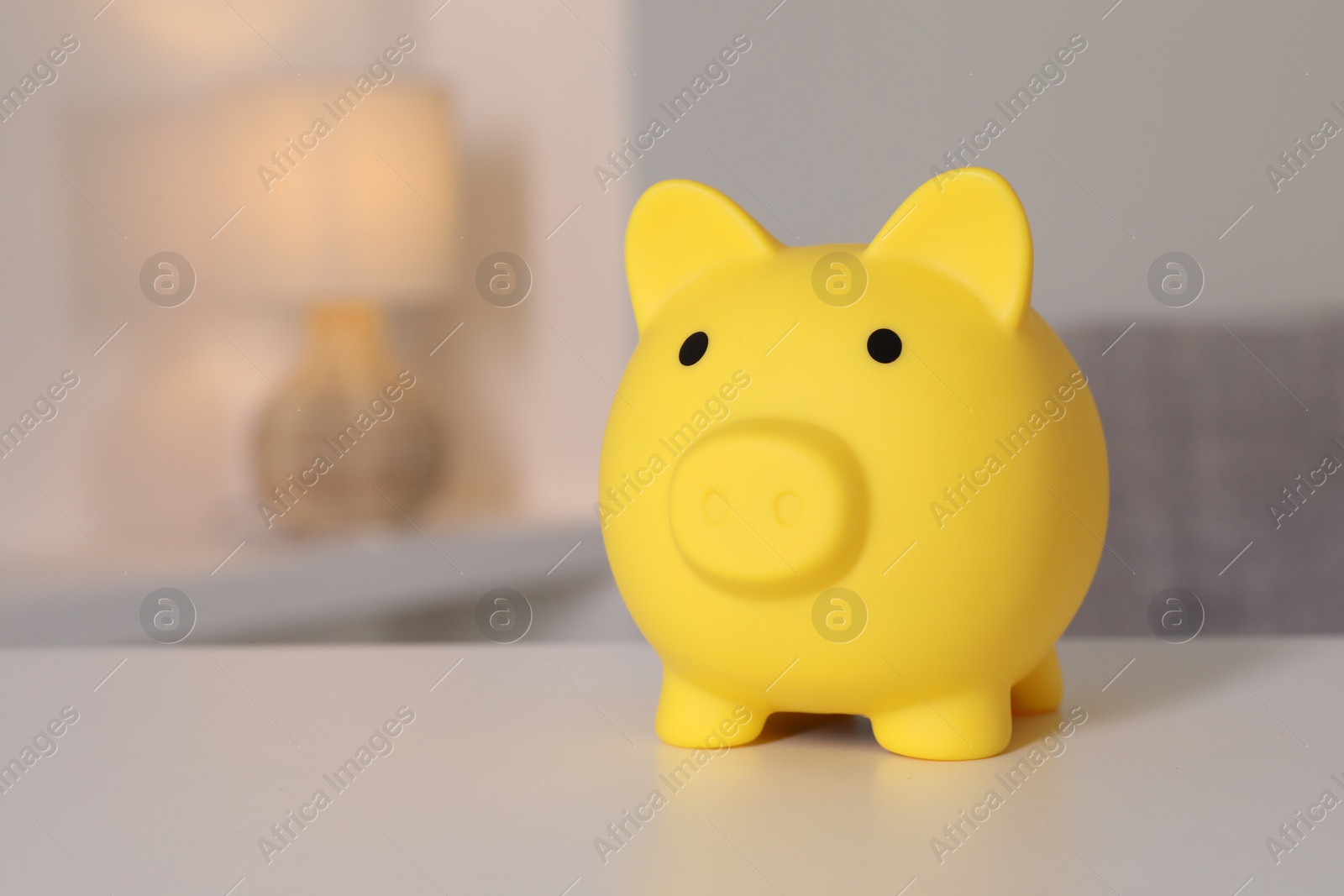 Photo of Yellow piggy bank on white table, space for text