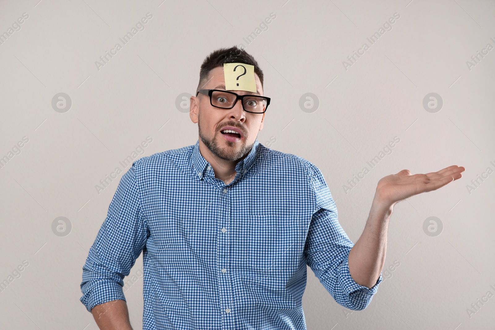 Photo of Emotional man in eyeglasses with question mark on grey background