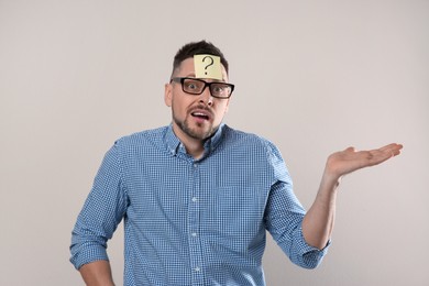 Photo of Emotional man in eyeglasses with question mark on grey background