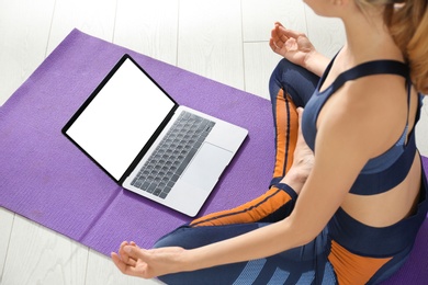 Photo of Woman having online video class via laptop at home, closeup. Distance yoga course during coronavirus pandemic
