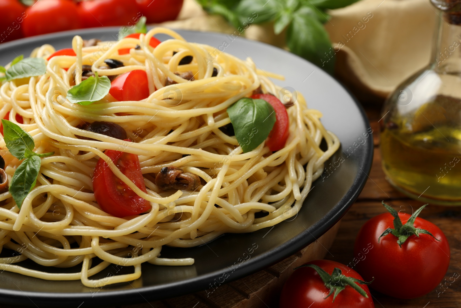 Photo of Delicious pasta with anchovies, tomatoes and olives on table, closeup