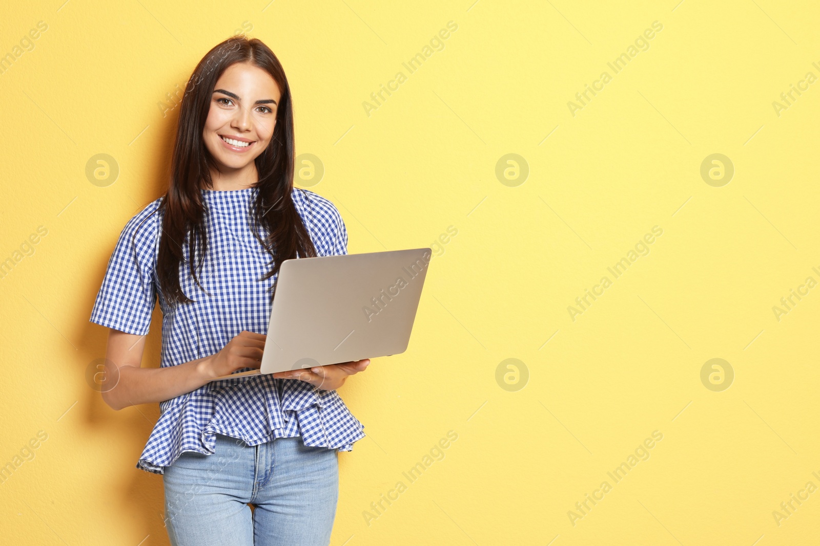 Photo of Young woman with modern laptop on color background