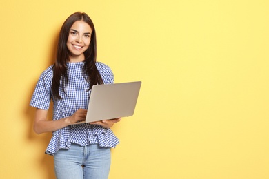 Photo of Young woman with modern laptop on color background