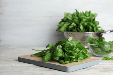 Wooden board with basil leaves on table. Space for text