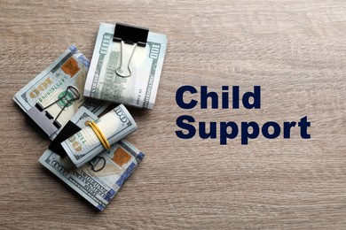 Child support concept. Many dollar banknotes on wooden table, flat lay