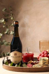 Bottle of red wine and delicious snacks on wooden table