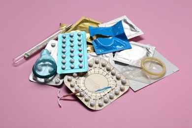 Photo of Contraceptive pills, condoms, intrauterine device and thermometer on pink background. Different birth control methods