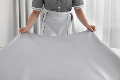 Photo of Maid making bed in hotel room, closeup