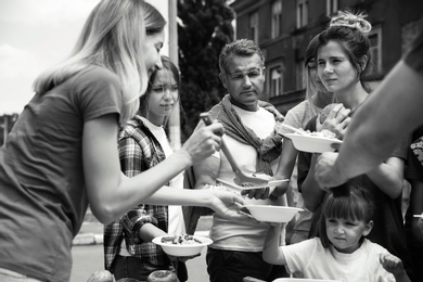 Photo of Volunteers serving food for poor people outdoors, black and white effect
