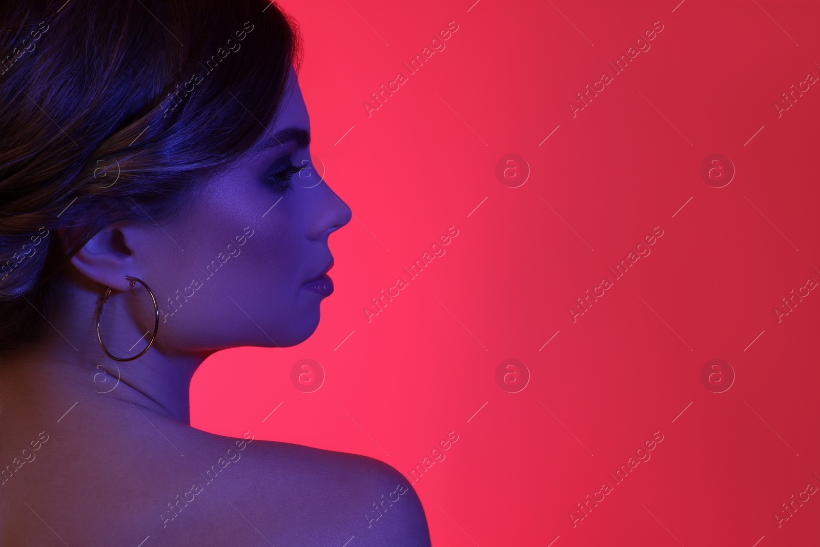 Photo of Fashionable portrait in neon lights. Beautiful young woman posing on dark pink background. Space for text