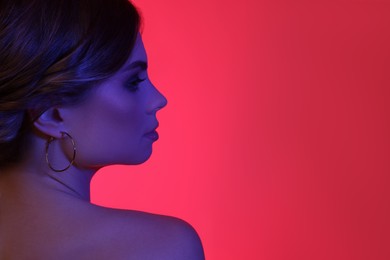 Photo of Fashionable portrait in neon lights. Beautiful young woman posing on dark pink background. Space for text