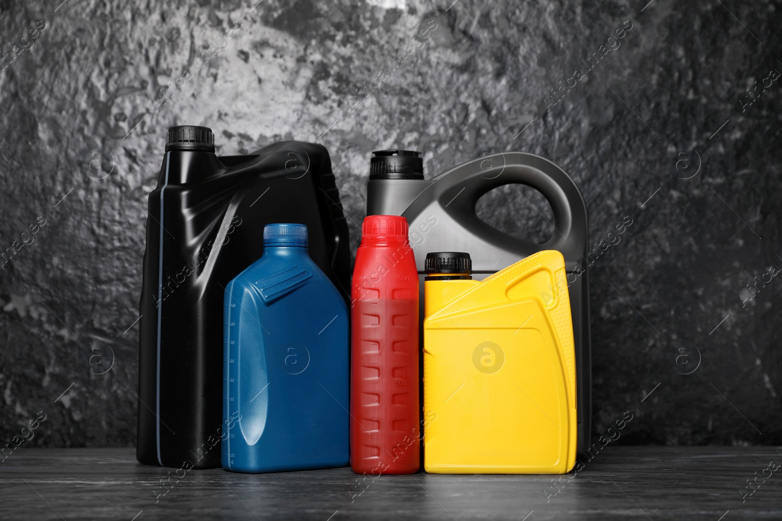 Photo of Motor oil in different canisters on black table near dark wall