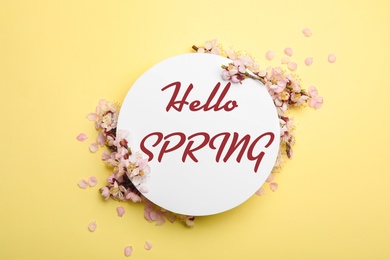 Beautiful flowers and card with text Hello Spring on yellow background, flat lay