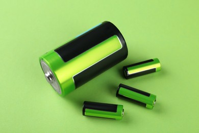 Image of Different batteries on light green background, above view