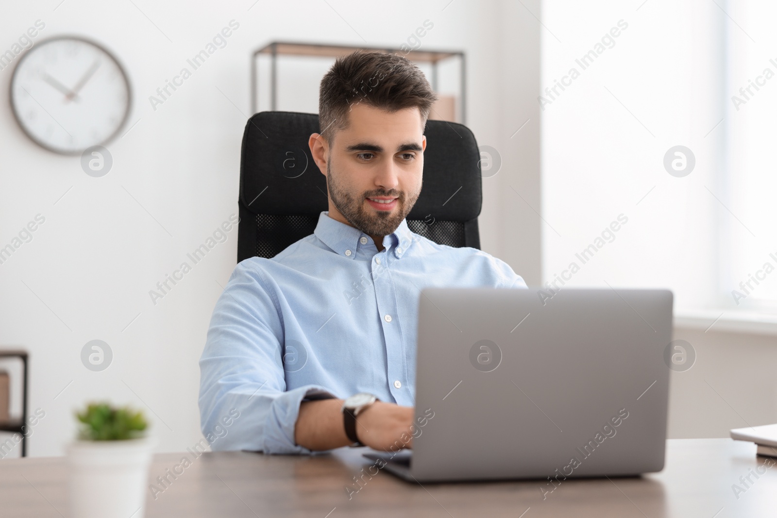 Photo of Happy young programmer working with laptop in office