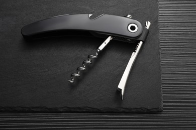 One corkscrew (sommelier knife) on black wooden table, top view