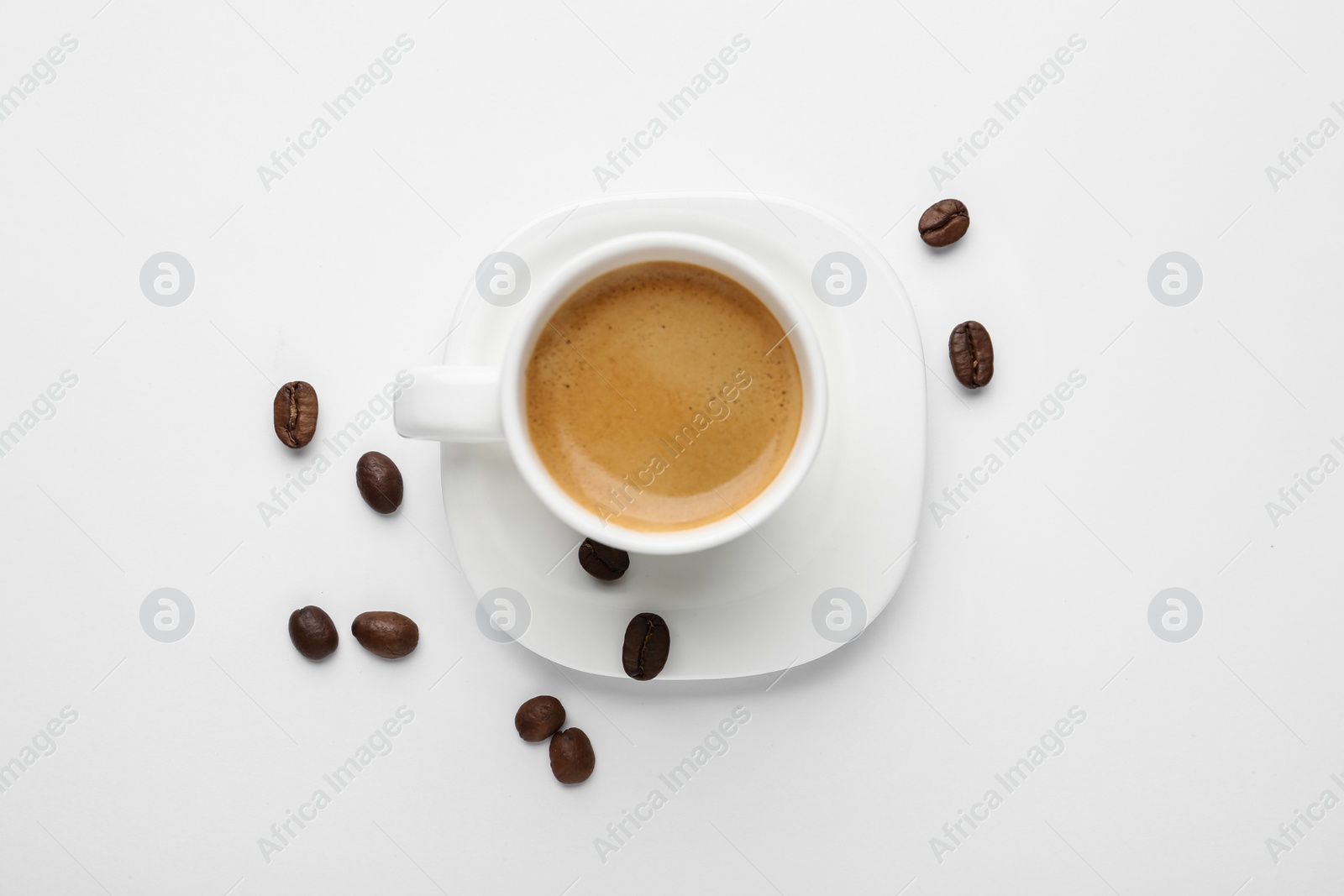 Photo of Scattered coffee beans and cup of hot espresso isolated on white, top view