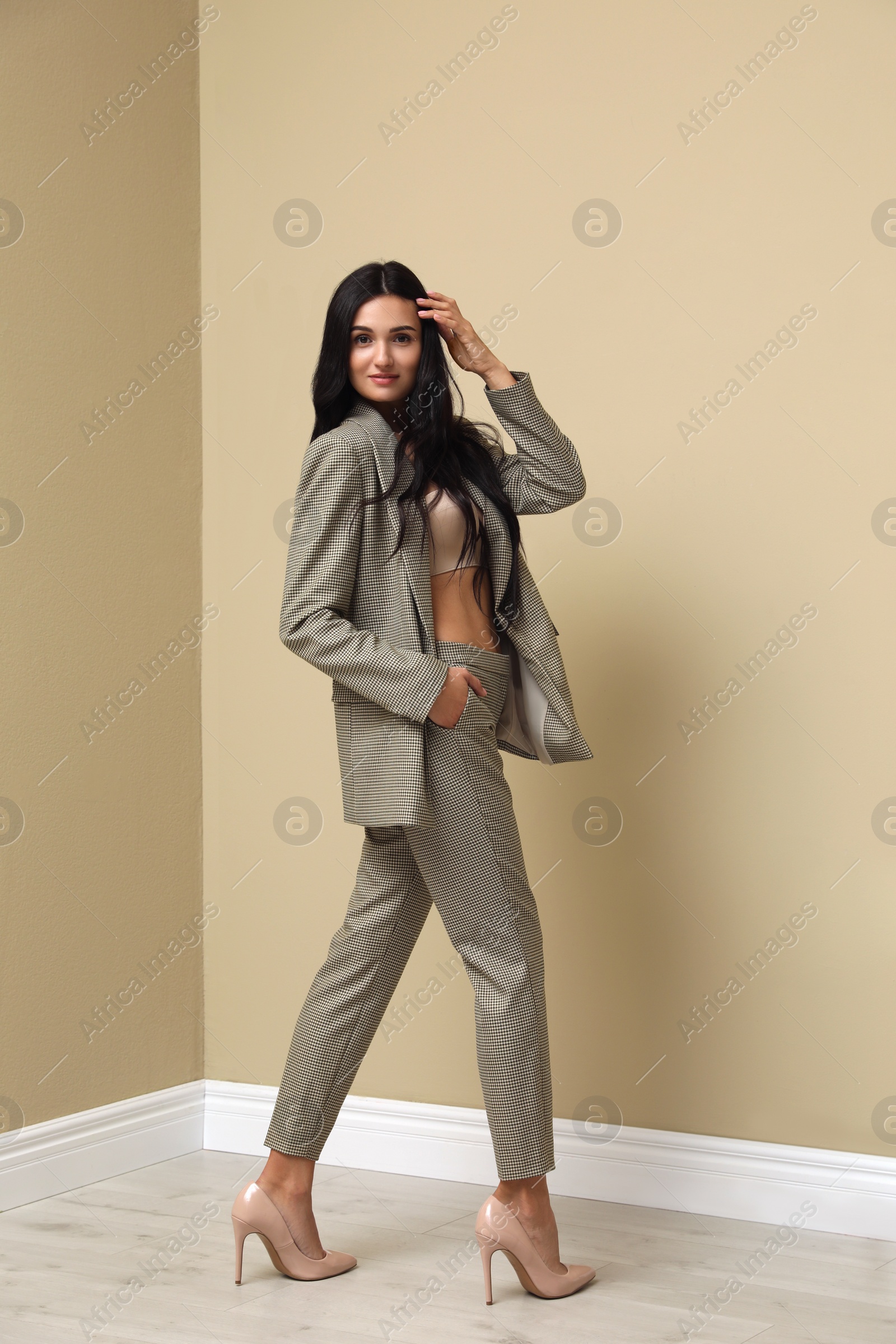 Photo of Full length portrait of beautiful woman in formal suit near beige wall