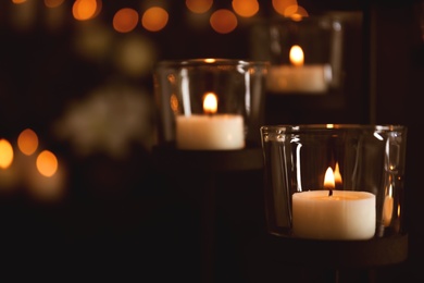 Burning candles on blurred background, space for text. Funeral symbol