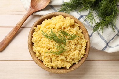 Tasty millet porridge and dill in bowl on light wooden table, flat lay