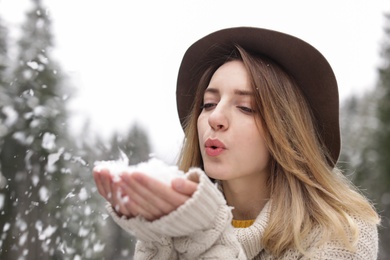 Photo of Young woman playing with snow outdoors. Winter vacation