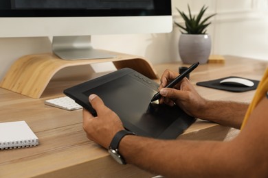 Professional retoucher working on graphic tablet at desk, closeup