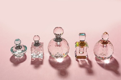 Different elegant perfume bottles on pink background