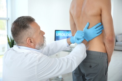 Photo of Urologist in gloves examining young patient in clinic