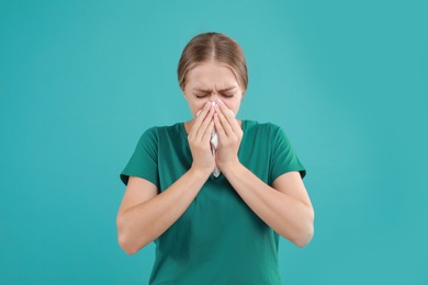 Photo of Young woman suffering from allergy on turquoise background