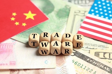 Wooden cubes with phrase Trade war on different banknotes near USA and China flags