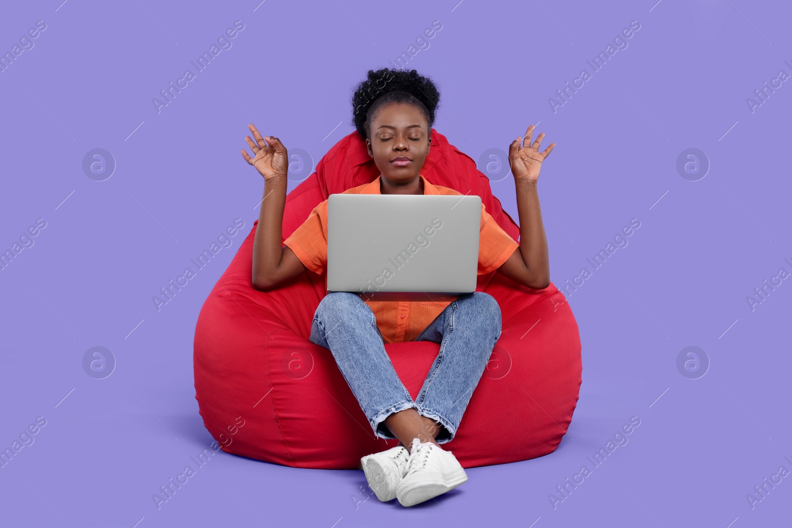 Photo of Young woman taking break from work on beanbag chair against purple background