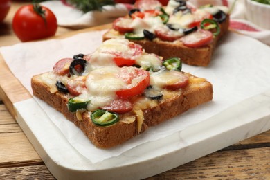 Tasty pizza toasts on wooden table, closeup