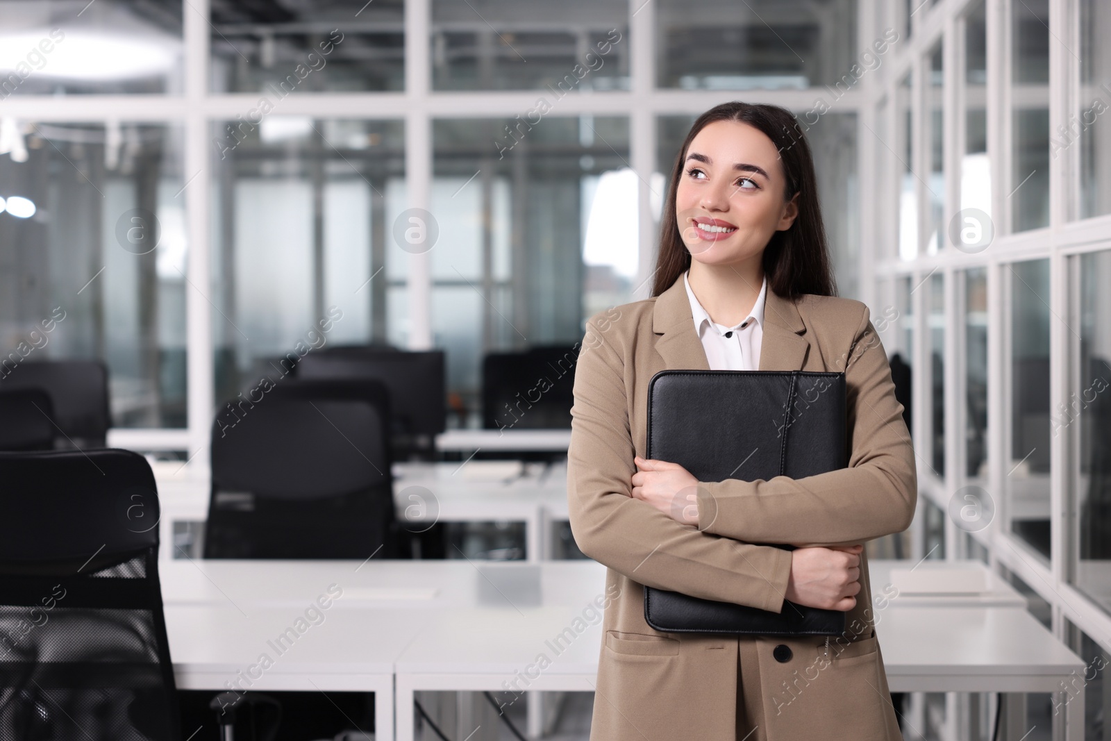 Photo of Happy real estate agent with leather portfolio indoors. Space for text