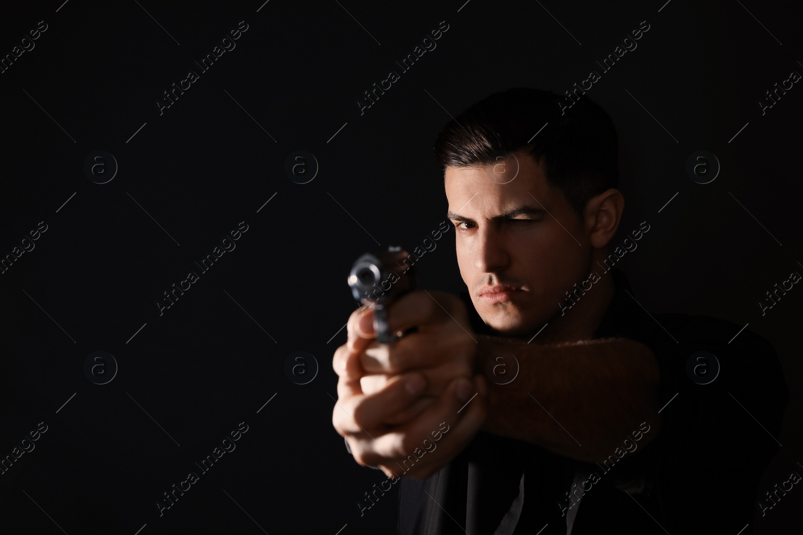 Photo of Professional killer with gun on black background