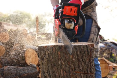 Man sawing wooden log on sunny day, closeup