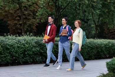 Happy young students walking together in park
