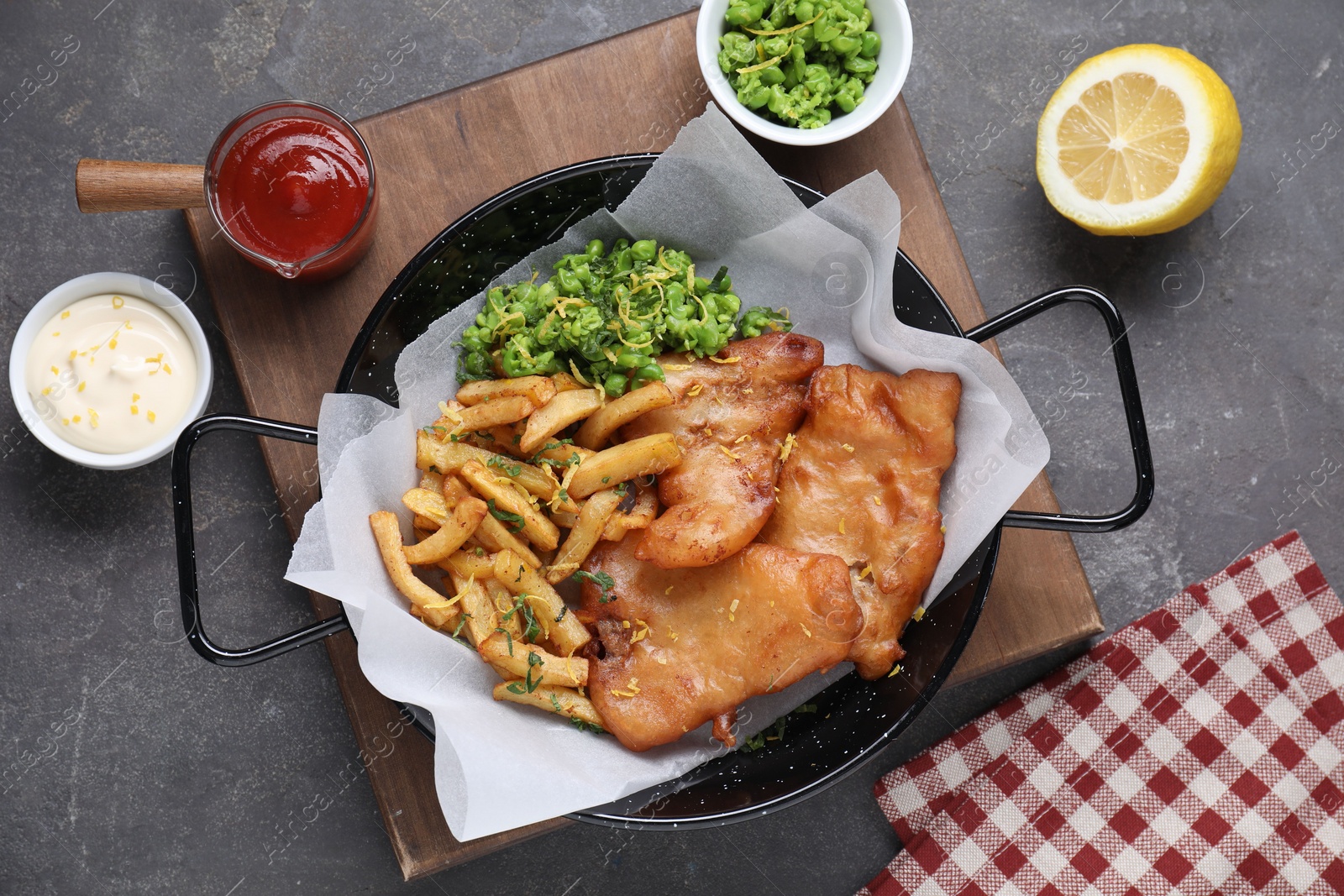 Photo of Tasty fish, chips, sauces and peas on grey table, flat lay